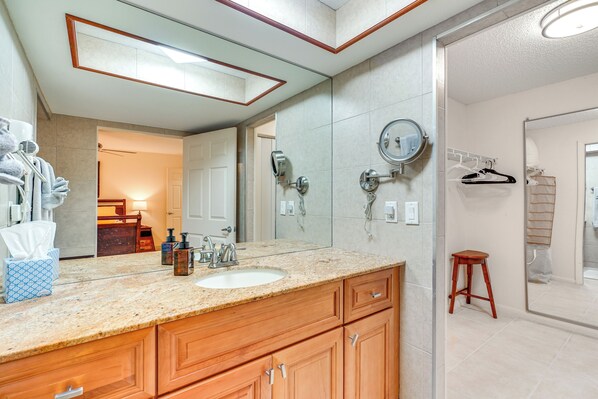 A bathroom with a granite countertop, wooden cabinets, a large mirror, and a towel rack.