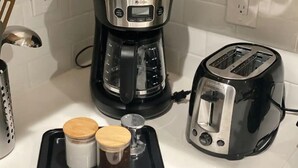 Une cuisine équipée d’une machine à café, d’un grille-pain et de deux bocaux disposés sur un plateau.