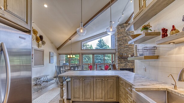 A modern kitchen with a large island, stainless steel appliances, and a stone accent wall. - Beautiful Townhouse near ski slopes, biking trail, & 1 mile from the main street (Park City)