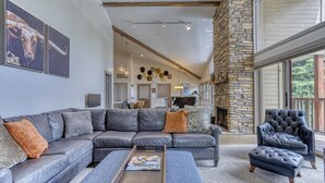 A modern living room with a stone fireplace, leather sofas, and a large window. - Beautiful Townhouse near ski slopes, biking trail, & 1 mile from the main street (Park City)