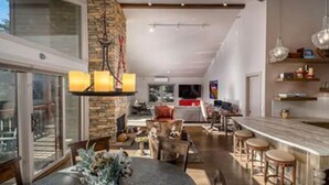 A modern kitchen with a stone accent wall, a dining area with a round table, and a bar area with stools. - Beautiful Townhouse near ski slopes, biking trail, & 1 mile from the main street (Park City)