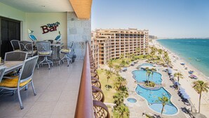 A hotel balcony with a view of the beach, a bar, and a pool area.