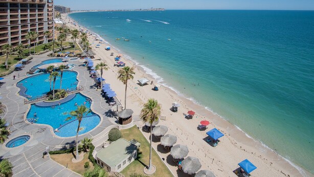 A resort with multiple swimming pools, a beach, and a view of the ocean.
