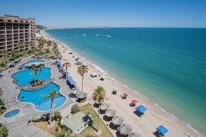 A resort with multiple swimming pools, a beach, and a view of the ocean.