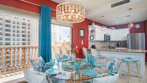 A modern kitchen with white cabinets, stainless steel appliances, and a dining area with a glass table and blue chairs.