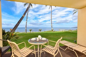 Relax in a serene beachfront setting with a seating area offering a view of the lawn and ocean.