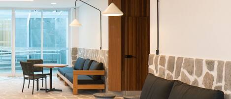 A modern living room with a stone-patterned floor, a sofa, a coffee table, and a dining area with chairs.