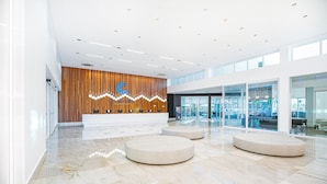 A modern lobby with a wooden reception desk, marble flooring, and large windows. - Exclusive - GAV Hotéis e Resorts (Salinópolis)