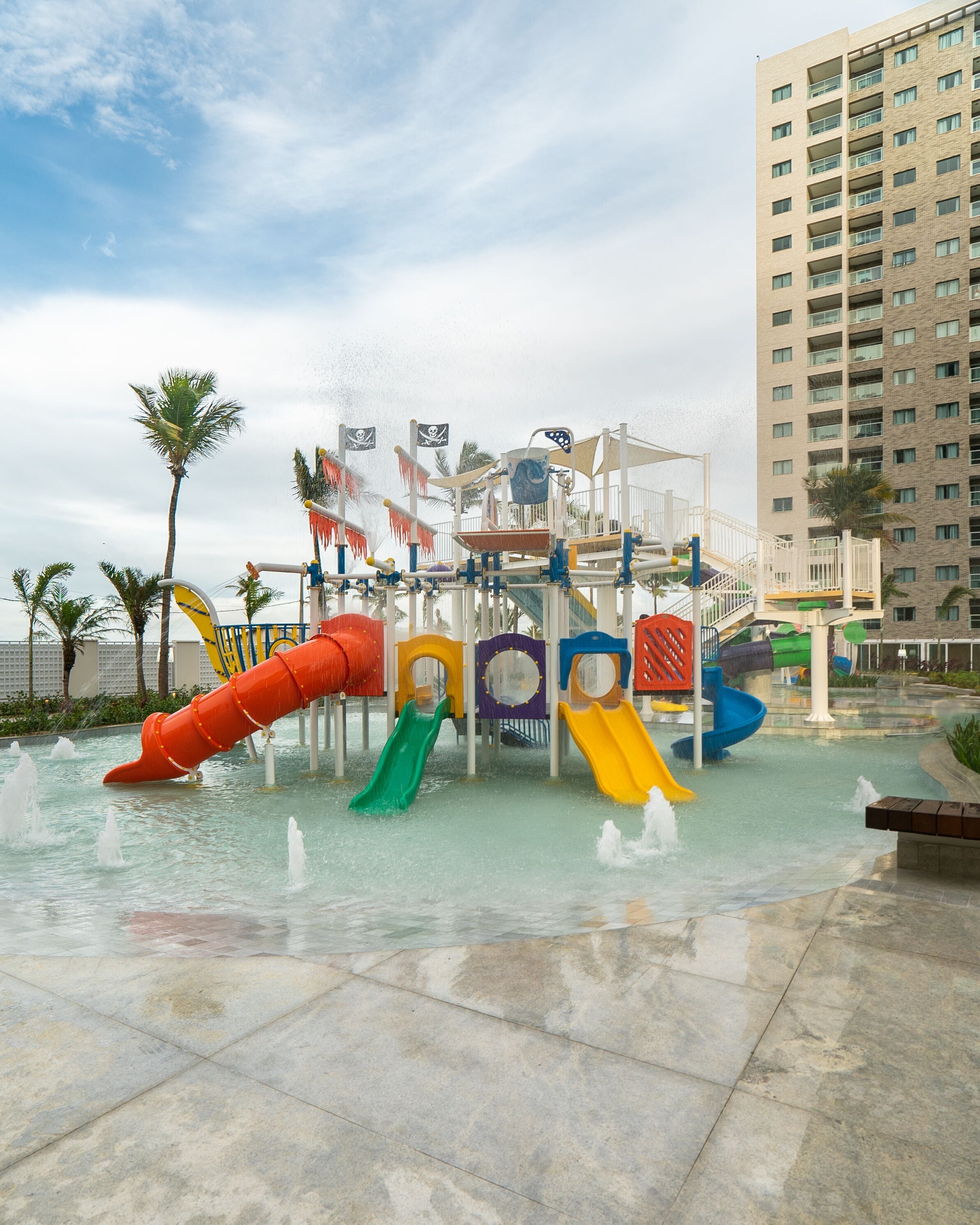 Un parque acuático con toboganes y un edificio alto al fondo.