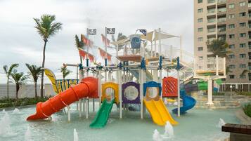Un parque acuático con toboganes y un edificio alto al fondo.