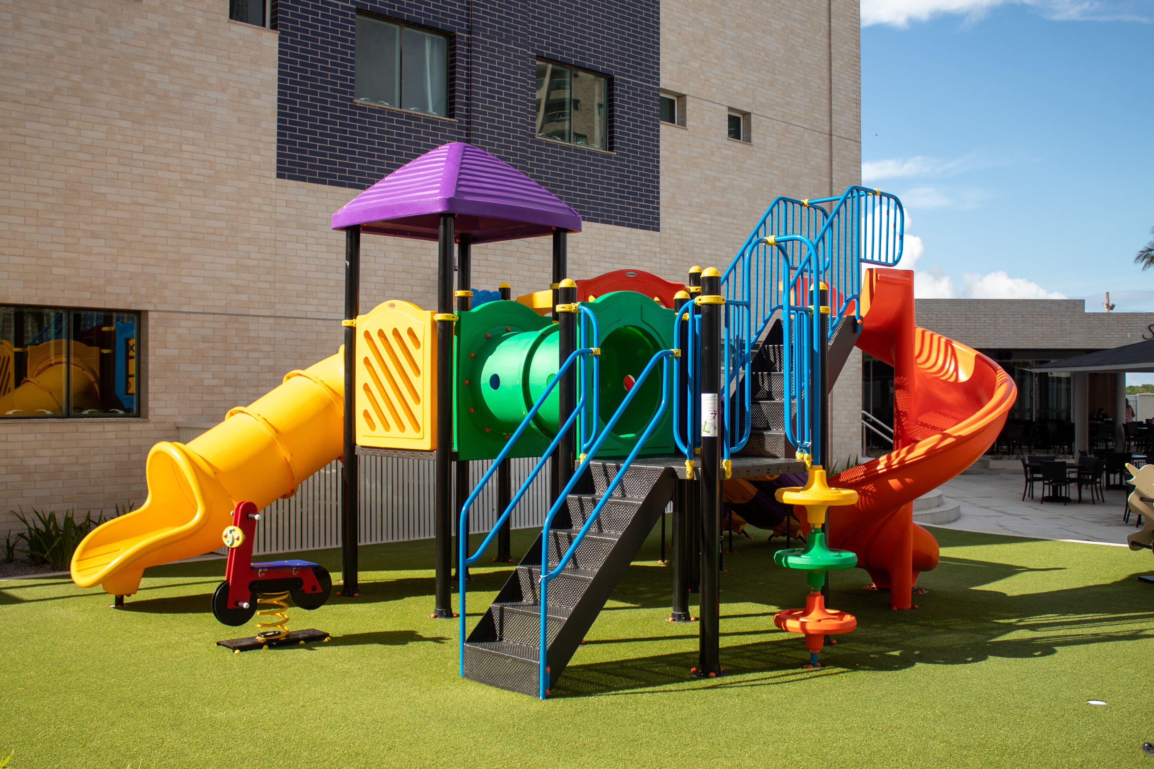 Un parque infantil con tobogán, estructura de escalada y zona cubierta.
