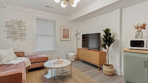 Un salon comprenant un canapé, un téléviseur, une table basse, un meuble et une plante en pot.