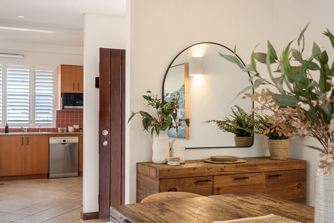 A modern kitchen with wooden cabinets, a dishwasher, and a dining area with a wooden table and chairs.