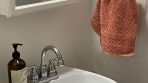 A bathroom with a white sink, a mirror, a towel ring, and a bottle of hand soap. - Cottage studio (Poway)