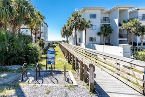 Stroll along the beachfront walkway, lined with lush greenery and palm trees, to reach the ocean's edge.
