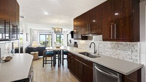 Una cocina moderna con gabinetes de madera oscura, encimera blanca y lavavajillas de acero inoxidable.