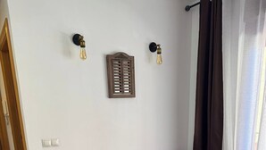 A grey sectional sofa with a woven rug and a small wooden table in a room with white walls, a wooden floor, and a window with curtains. - Sunny Seaside Apartment in Aguadulce (AGUADULCE)
