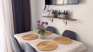 A dining area with a table set for four, featuring woven placemats and a vase of purple flowers. - Sunny Seaside Apartment in Aguadulce (AGUADULCE)