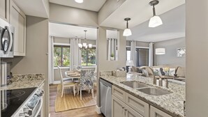 Cozinha moderna com bancadas de granito, eletrodomésticos de aço inoxidável e iluminação pendente.