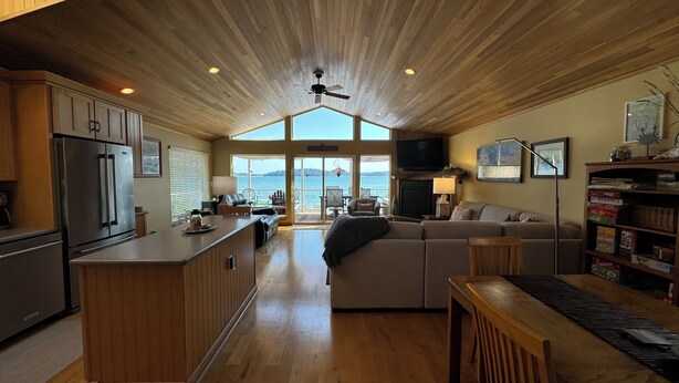 A spacious kitchen with wooden cabinets, a large island, and a view of the water through the open sliding doors. - Waterfront home, steps to the beach in protected bay!  Birding, kayaking, swim. (Anacortes)