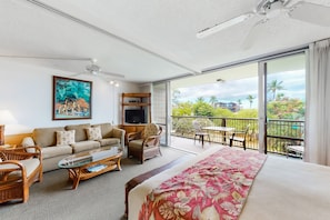 Relax in this stylish room with a large bed, sofa, and balcony offering views of palm trees and buildings.