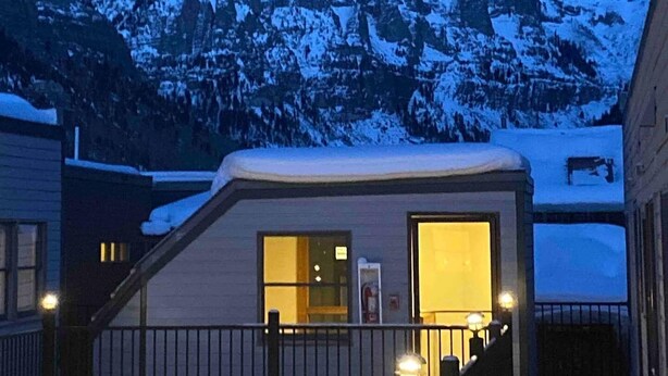 A building with a snow-covered roof and a view of a snow-capped mountain in the background.