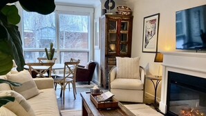 A living room with a sofa, chairs, a coffee table, a fireplace, and a window with a cactus on the windowsill.