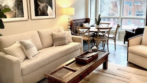 A living room with a sofa, coffee table, and a dining area with chairs and a table.