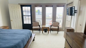 A bedroom with a bed, a dresser, two chairs, a small table, and a TV mounted on the wall. - South Haven Condo w/ LAKE MICHIGAN + LIGHTHOUSE VIEWS w/ POOL + PRIVATE BEACH  (South Haven)