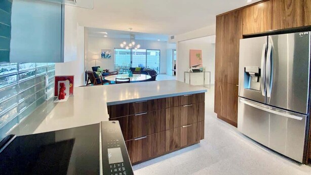 A modern kitchen with a central island, stainless steel appliances, and a view to a dining area. - Modern Treat: Stunning Remodeled Townhome (Palm Springs)