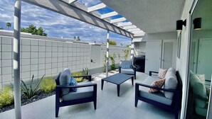 A covered patio with outdoor furniture, a grill, and a view of the sky. - Modern Treat: Stunning Remodeled Townhome (Palm Springs)