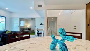 A modern living room with a marble table, a teal balloon sculpture, and a view into the dining area. - Modern Treat: Stunning Remodeled Townhome (Palm Springs)