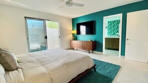 A bedroom with a bed, a TV, a wardrobe, and a sliding door to a balcony. - Modern Treat: Stunning Remodeled Townhome (Palm Springs)