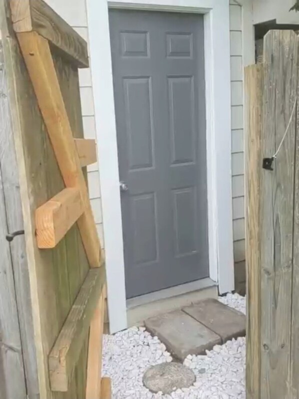 Enter through the central door, flanked by gates, onto a gravel pathway.