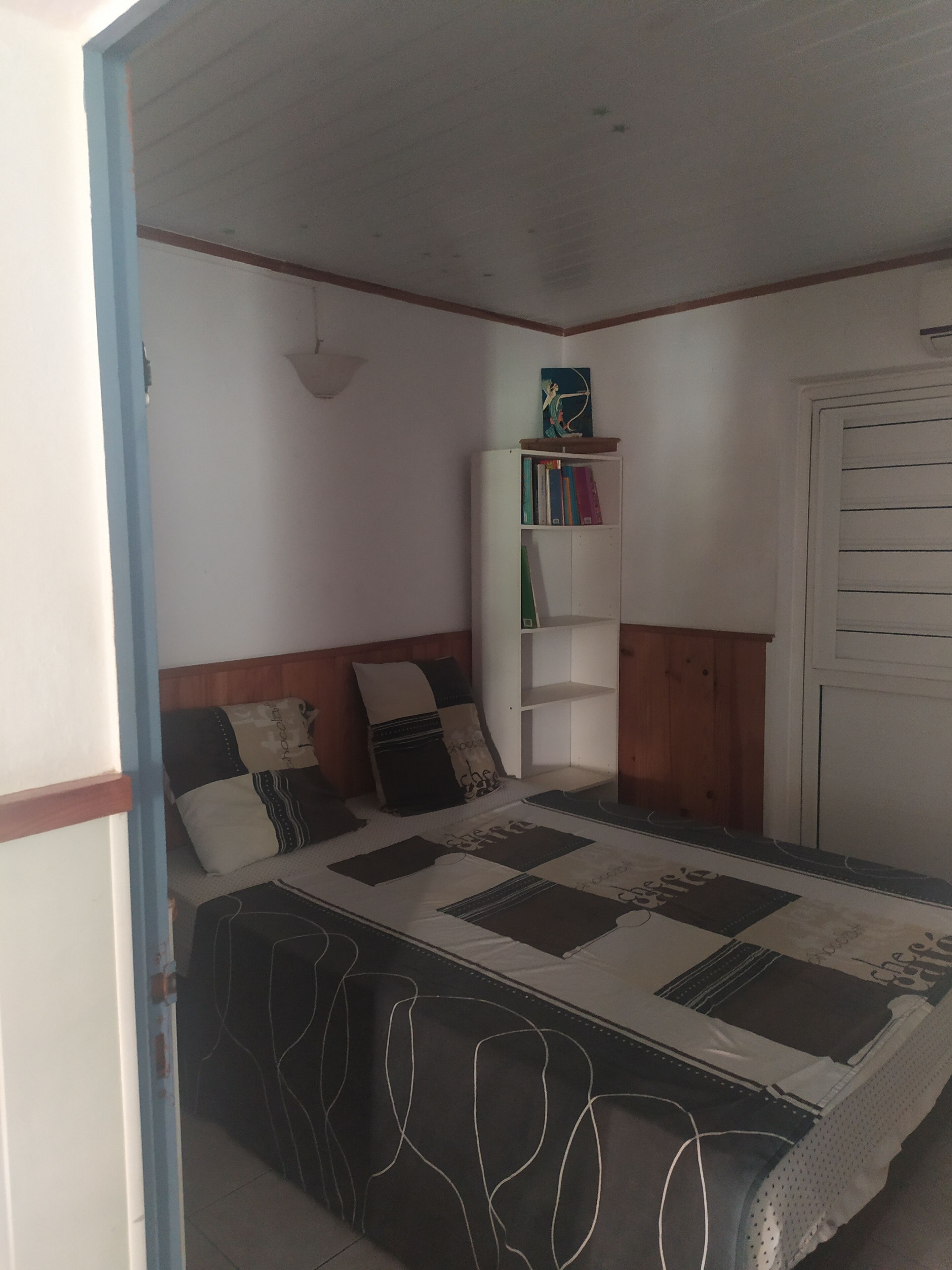 A bedroom with a bed, a bookshelf, and a wardrobe.