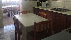 A kitchen with a dining table, chairs, a microwave, a coffee maker, and a gas stove.