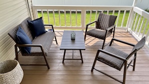 A wooden deck with wicker furniture, including a sofa and two chairs, and a small table. - Eastside Modern Farmhouse in downtown Kalispell (Kalispell)