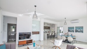 A modern living room with a TV, sofas, and a dining area with chairs and a table. - Villa Prol21,fantastic 3bdr Protaras Villa with Pool,close to Fig Tree Bay Beach (Protaras)