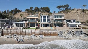 A beachfront property with multiple modern houses, a wooden deck, and a rocky shoreline. - Beach access escape w/ oceanfront deck- STR16-0534 (Dana Point)