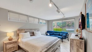 A bedroom with a large bed, a nightstand, a blue sofa, and a desk with a lamp. - Beach access escape w/ oceanfront deck- STR16-0534 (Dana Point)