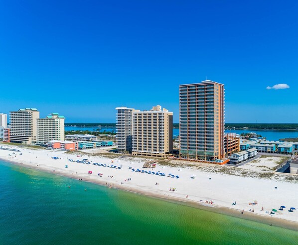 A coastal cityscape with high-rise buildings, a sandy beach, and a clear blue sky.