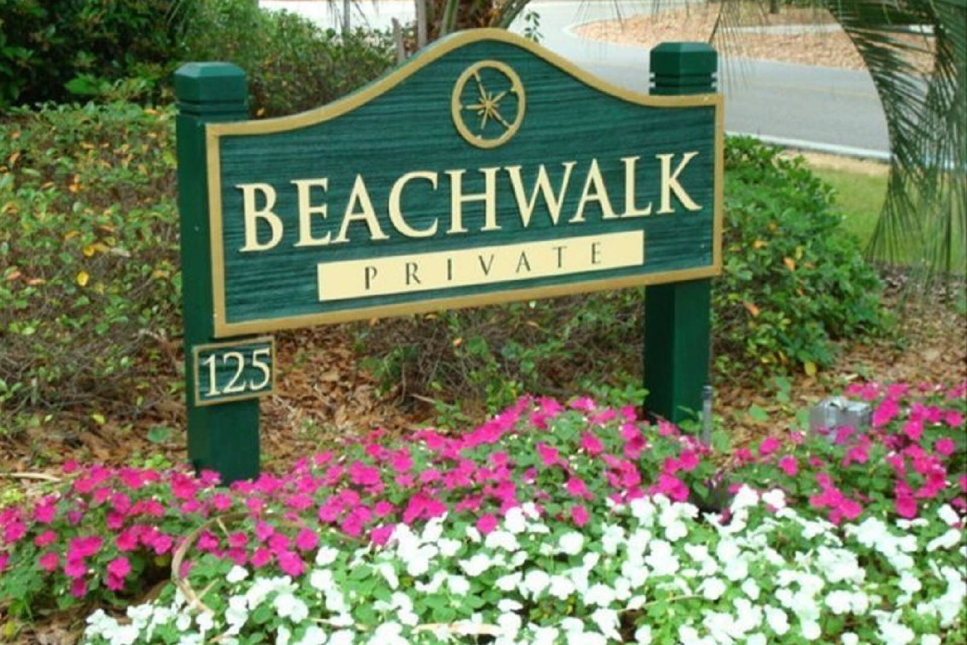 A private beachwalk sign with the number 125, surrounded by pink and white flowers.