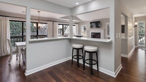 Une cuisine moderne avec un coin bar, deux tabourets et une cheminée.