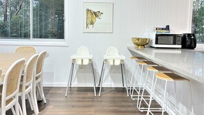 Una cocina moderna con armarios blancos, un ventanal grande, un microondas y un bol en la encimera.