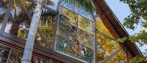 A conservatory with a glass ceiling, reflecting surrounding trees and sky.