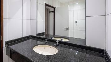 A bathroom with two sinks, a large mirror, and white tiled walls.