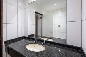 A bathroom with two sinks, a large mirror, and white tiled walls.
