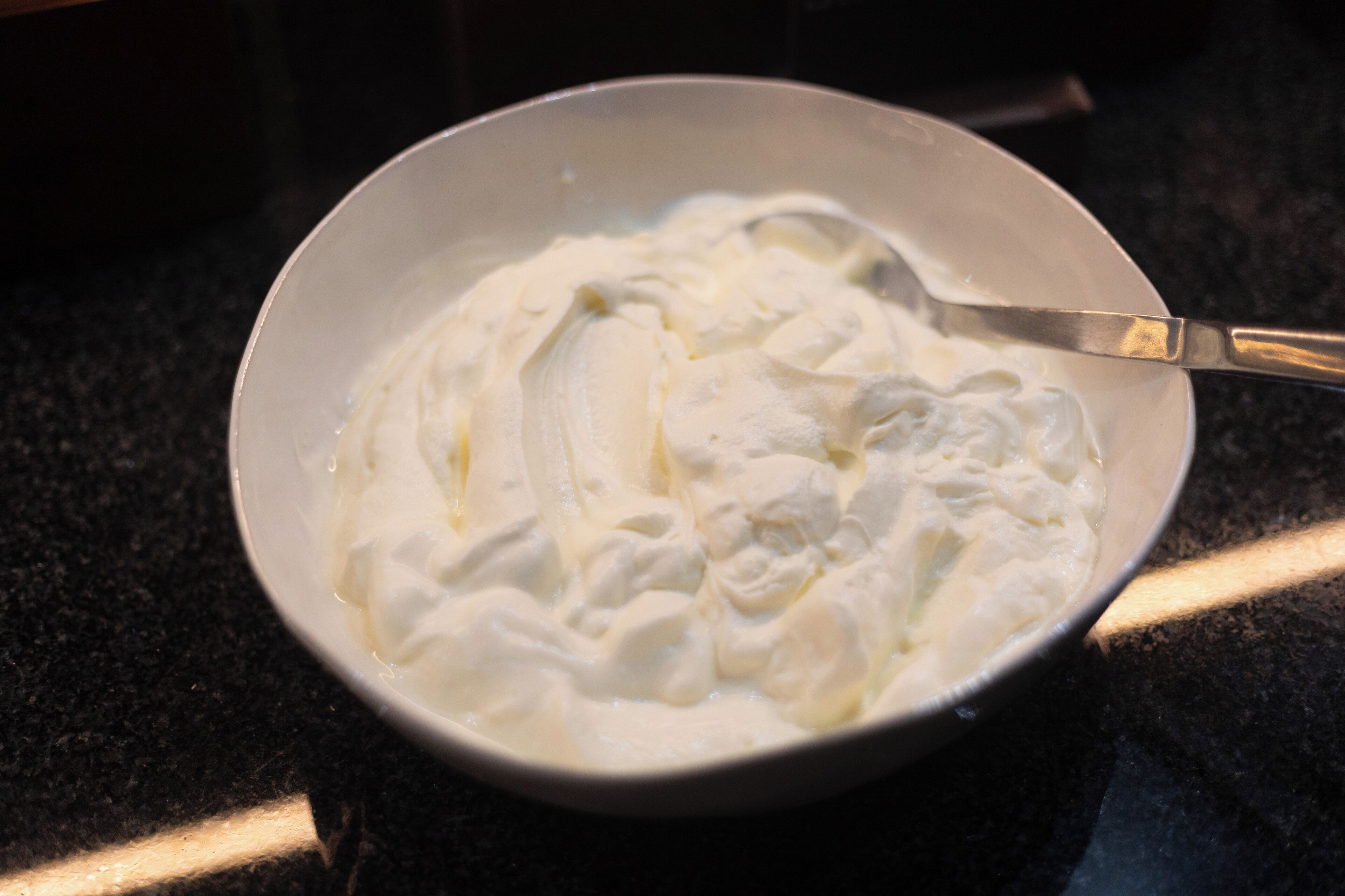 A bowl of creamy substance on a dark countertop.