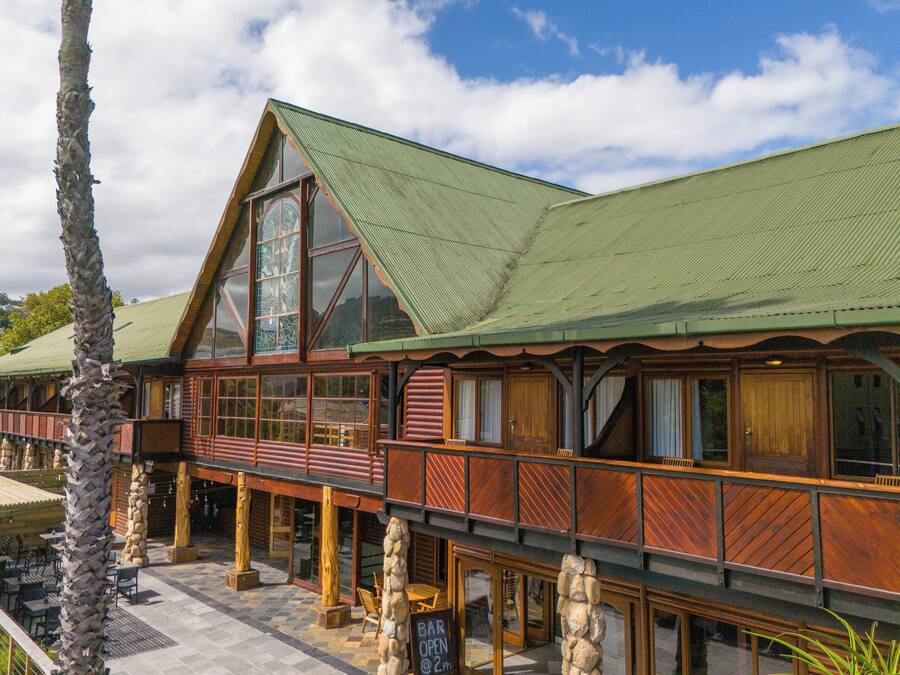 Un edificio de madera con techo verde, ventanas amplias y un balcón con barandilla de madera.