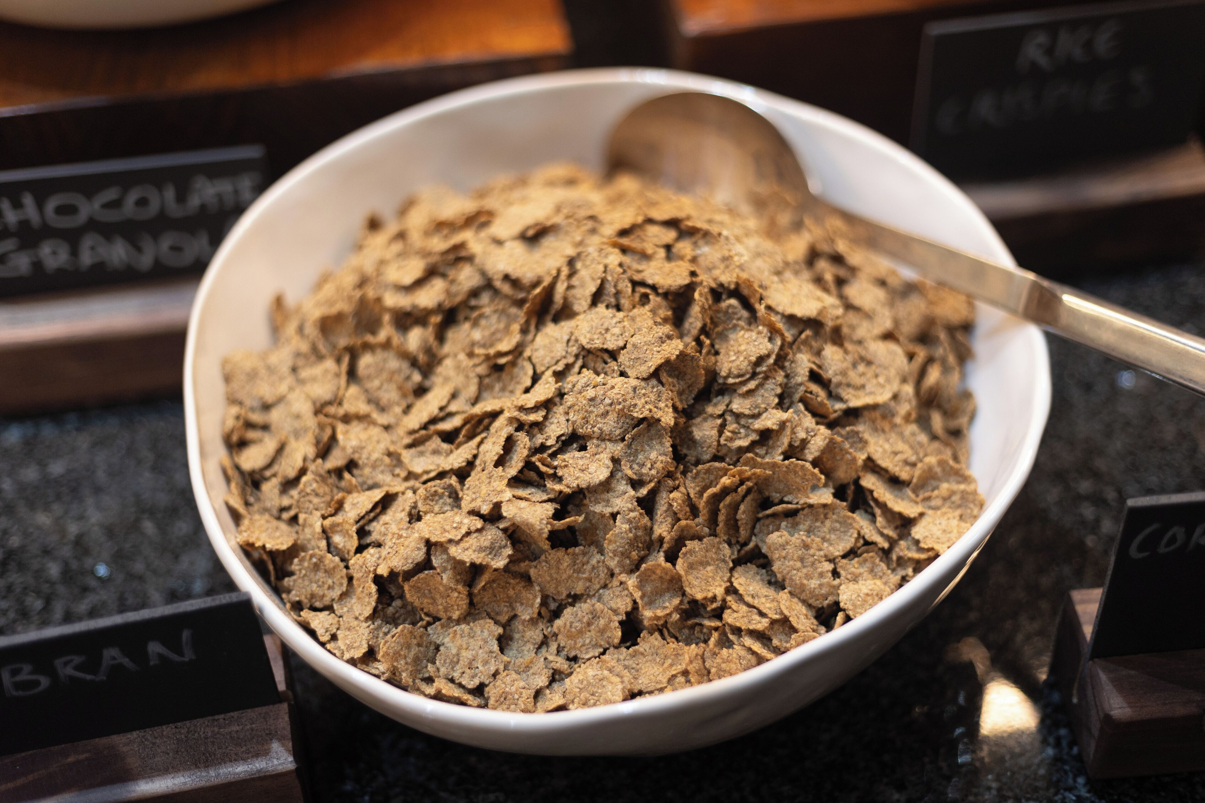A bowl of cereal with a spoon, placed on a counter with labels indicating different types of cereal.